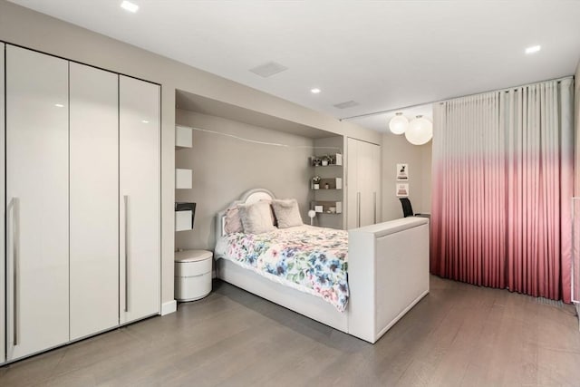 bedroom with multiple closets and hardwood / wood-style floors