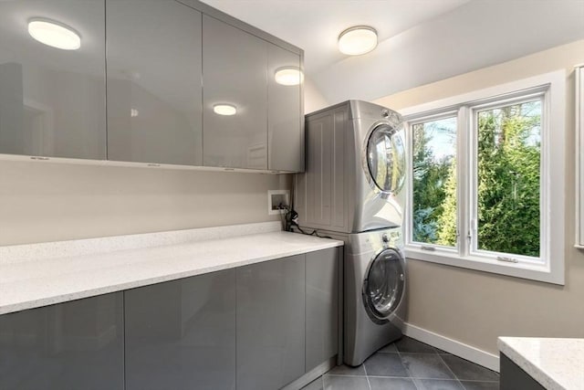 washroom featuring cabinets, tile patterned floors, and stacked washer / drying machine