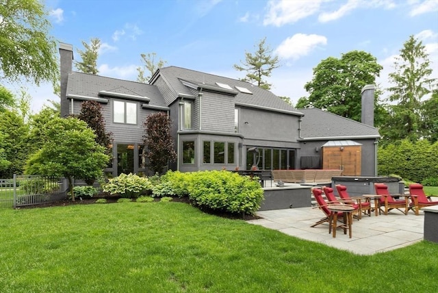 rear view of house with a lawn, a patio area, and a hot tub