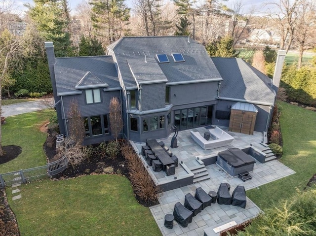 rear view of property with a lawn, an outdoor living space with a fire pit, and a patio