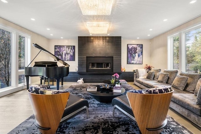 living room featuring a fireplace, a notable chandelier, light hardwood / wood-style floors, and a healthy amount of sunlight