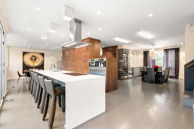 kitchen featuring island exhaust hood, a large island with sink, stainless steel oven, black electric cooktop, and sink