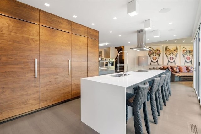 kitchen featuring sink, a breakfast bar, island exhaust hood, and a spacious island