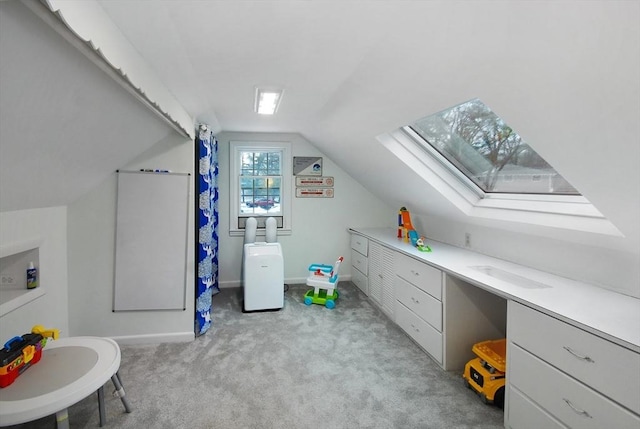 interior space with vaulted ceiling with skylight, light carpet, and baseboards