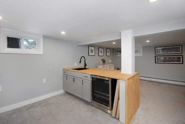 kitchen with light colored carpet, beverage cooler, a baseboard heating unit, a sink, and wooden counters