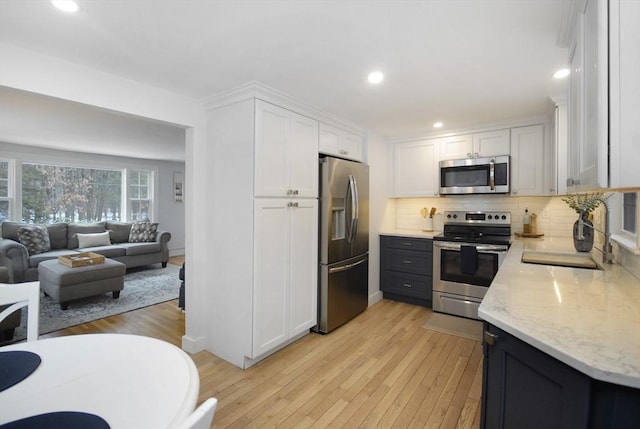 kitchen with stainless steel appliances, tasteful backsplash, a sink, and white cabinets