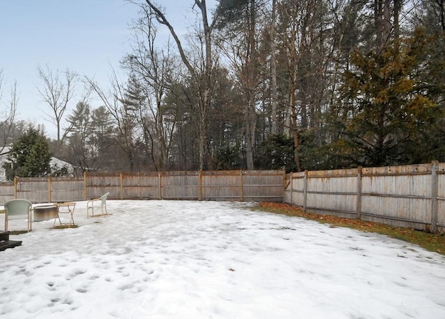 snowy yard featuring a fenced backyard