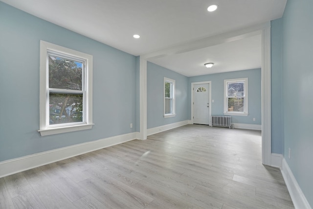 interior space featuring radiator, light wood-type flooring, and plenty of natural light