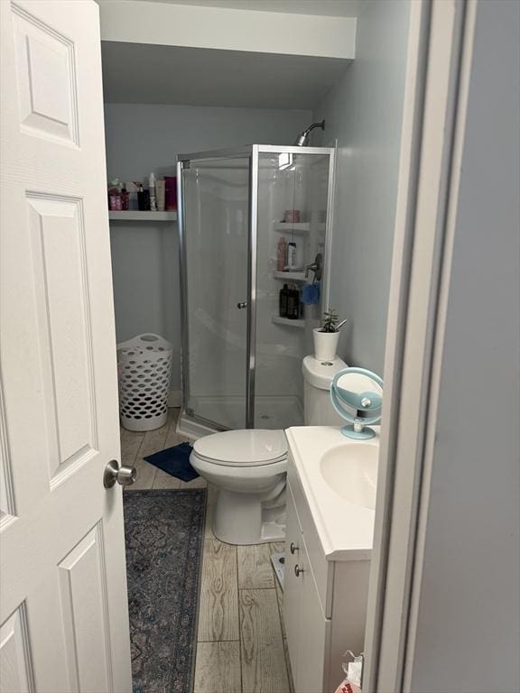 bathroom featuring vanity, hardwood / wood-style flooring, a shower with door, and toilet