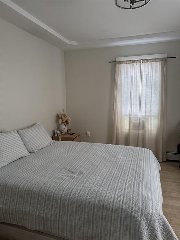 bedroom with a baseboard radiator and light hardwood / wood-style flooring