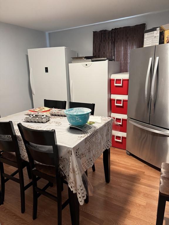 kitchen featuring stainless steel refrigerator, white refrigerator, dark brown cabinets, and light wood-type flooring