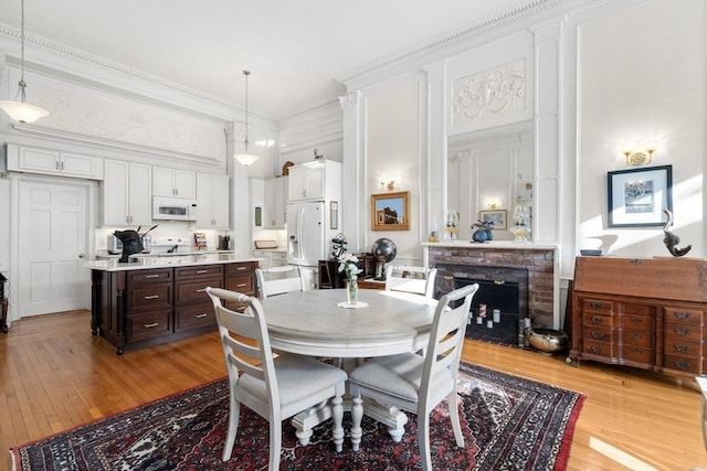 dining space with a fireplace, light hardwood / wood-style floors, and ornamental molding