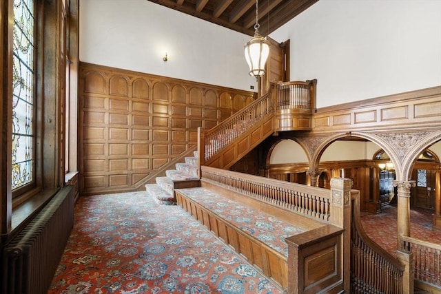 interior space with beamed ceiling, a high ceiling, and radiator