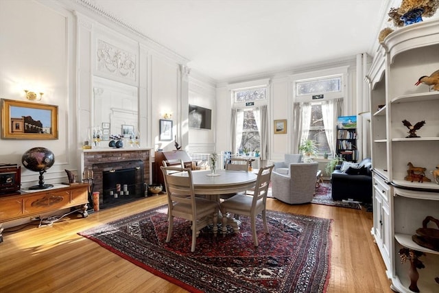 dining space with crown molding, a fireplace, and light wood-type flooring