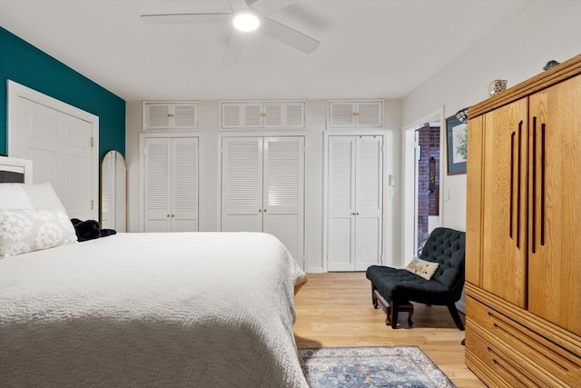 bedroom with ceiling fan, light wood-type flooring, and multiple closets