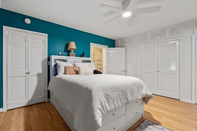 bedroom featuring wood-type flooring, two closets, and ceiling fan