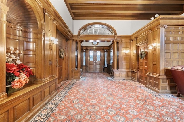 hallway featuring ornamental molding, french doors, wooden walls, and decorative columns