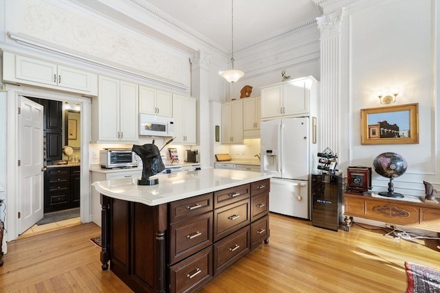 kitchen featuring white cabinetry, dark brown cabinetry, white appliances, and hanging light fixtures