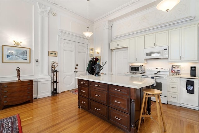 kitchen featuring a kitchen bar, white appliances, crown molding, white cabinetry, and hanging light fixtures