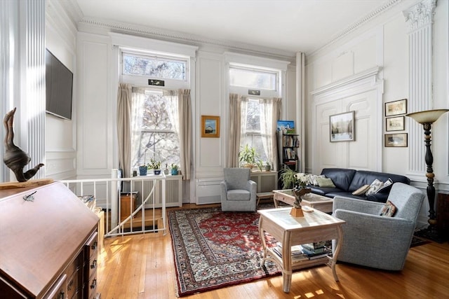 living area with plenty of natural light, light hardwood / wood-style floors, and crown molding