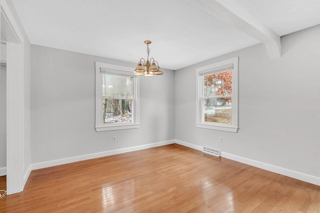 unfurnished dining area with a chandelier, light wood-style flooring, and baseboards