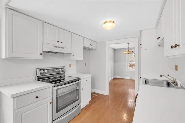 kitchen with baseboards, under cabinet range hood, electric range, white cabinetry, and a sink