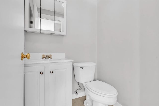 bathroom with toilet, vanity, and baseboards