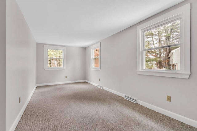 empty room featuring visible vents, baseboards, and carpet