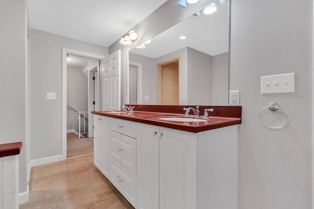 bathroom with double vanity, baseboards, and a sink