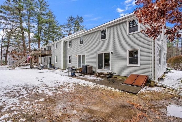 snow covered back of property featuring central air condition unit, entry steps, stairway, and a patio area