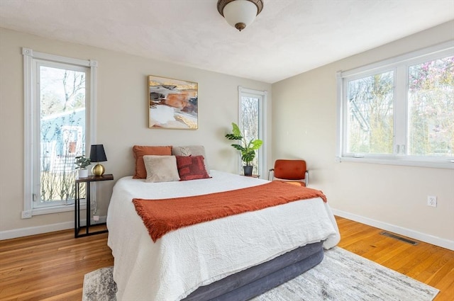 bedroom featuring wood finished floors, visible vents, and baseboards