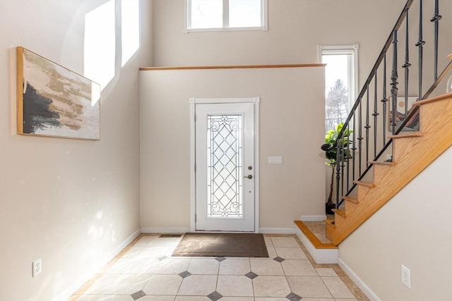 foyer featuring light tile patterned flooring, stairway, and a wealth of natural light