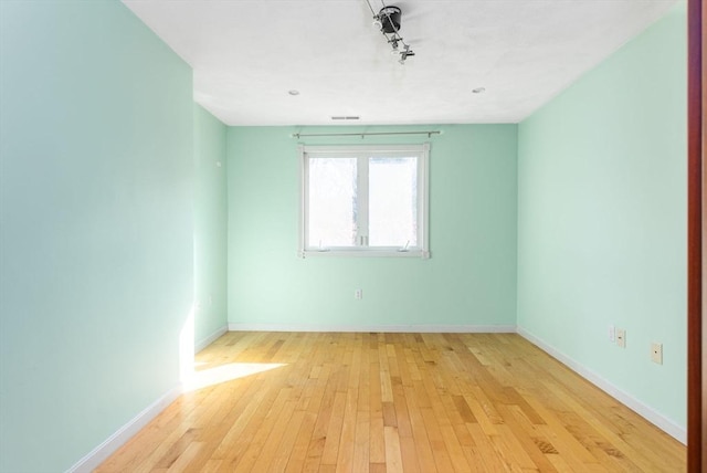 empty room featuring light wood-type flooring, baseboards, and visible vents