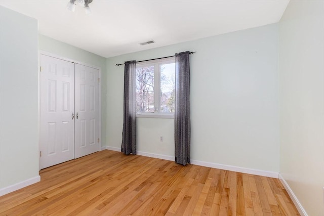 unfurnished bedroom featuring a closet, light wood-type flooring, visible vents, and baseboards