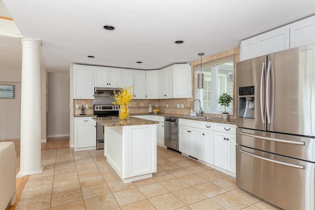kitchen with stainless steel appliances, decorative columns, decorative backsplash, and white cabinetry