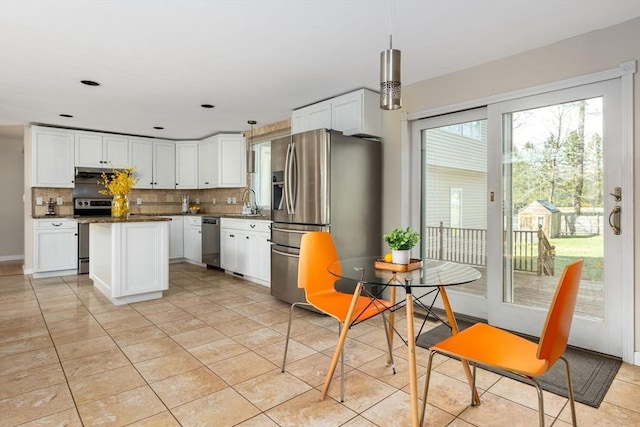 kitchen with white cabinets, stainless steel appliances, a center island, tasteful backsplash, and dark countertops