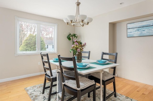 dining room featuring light wood-style flooring, baseboards, and a notable chandelier