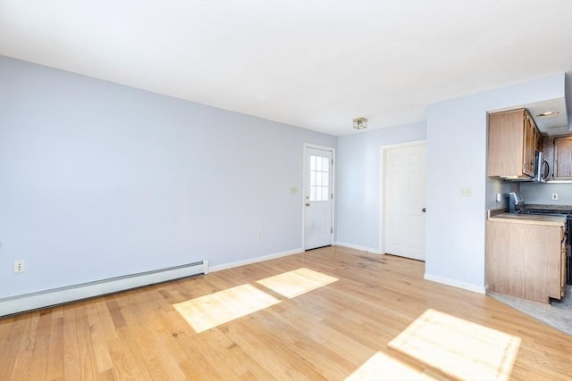 unfurnished living room featuring a baseboard heating unit and light wood-type flooring