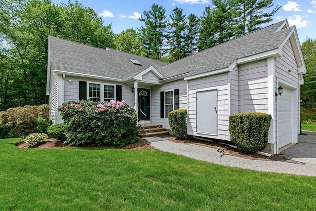 ranch-style house with roof with shingles, an attached garage, and a front lawn