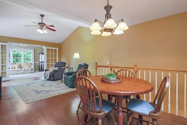 dining room featuring a ceiling fan, vaulted ceiling, a chandelier, and wood finished floors