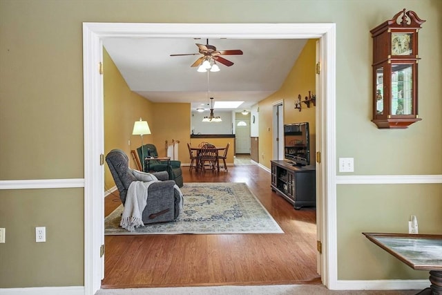 living room with a ceiling fan, wood finished floors, and baseboards
