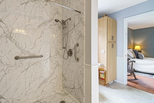 bathroom featuring a marble finish shower, a wainscoted wall, ensuite bathroom, tile patterned floors, and a decorative wall