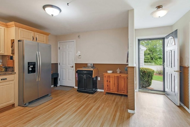 kitchen featuring stainless steel fridge, light wood-style floors, light brown cabinetry, wainscoting, and dark countertops