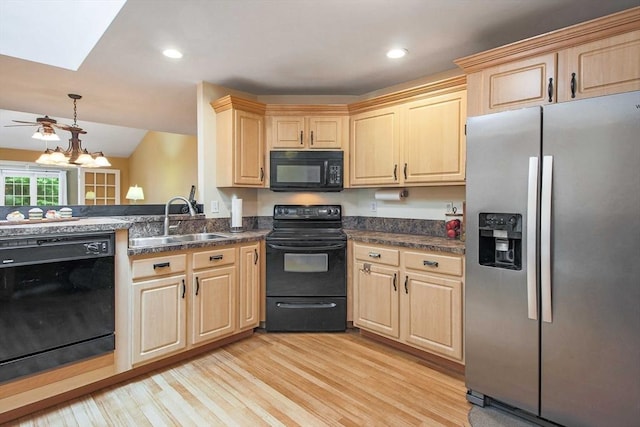 kitchen featuring black appliances, a sink, light brown cabinetry, light wood-type flooring, and recessed lighting