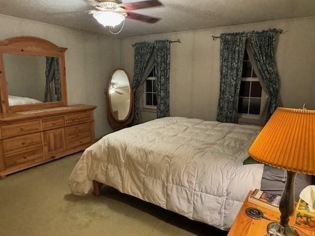 bedroom featuring ceiling fan, light colored carpet, and a textured ceiling