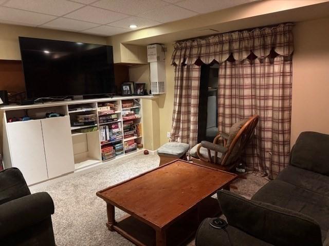 living area with a drop ceiling and carpet flooring