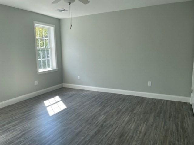 spare room featuring visible vents, baseboards, a ceiling fan, and dark wood-style flooring