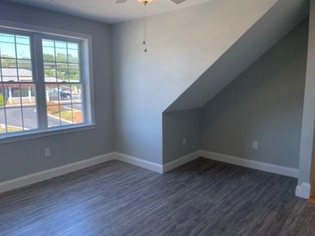 additional living space featuring a wealth of natural light, dark wood finished floors, baseboards, and ceiling fan