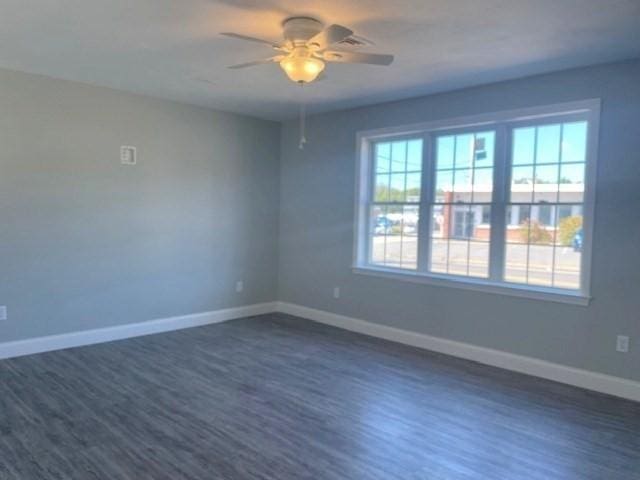 unfurnished room featuring dark wood-style floors, ceiling fan, and baseboards