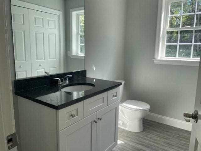 bathroom with toilet, vanity, baseboards, and wood finished floors